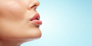 Side profile close-up of a woman pursing her lips to show off the results of her lip lift treatment.